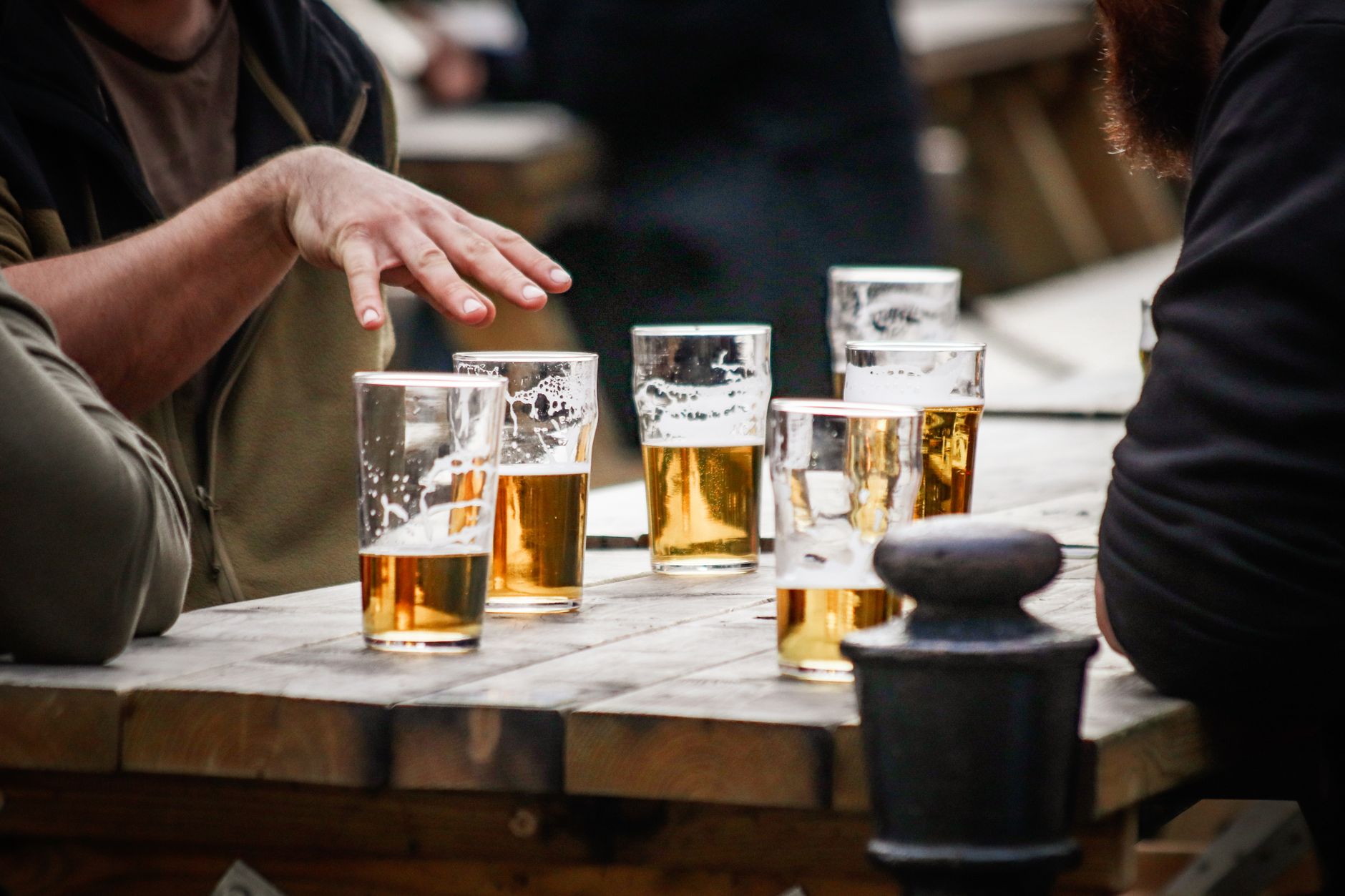 people sitting by table with cups of beer