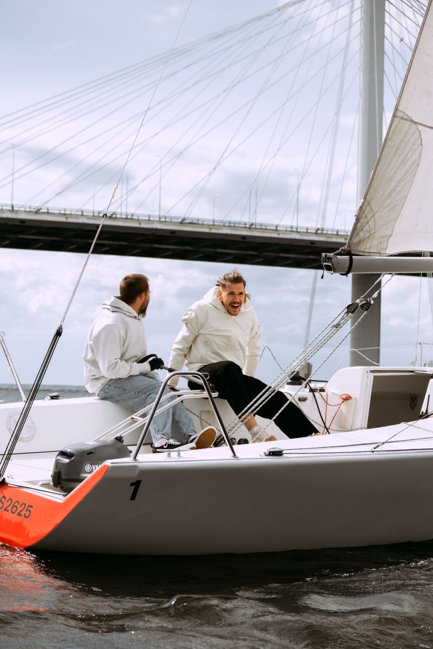 man in white dress shirt and black pants sitting on white and red boat