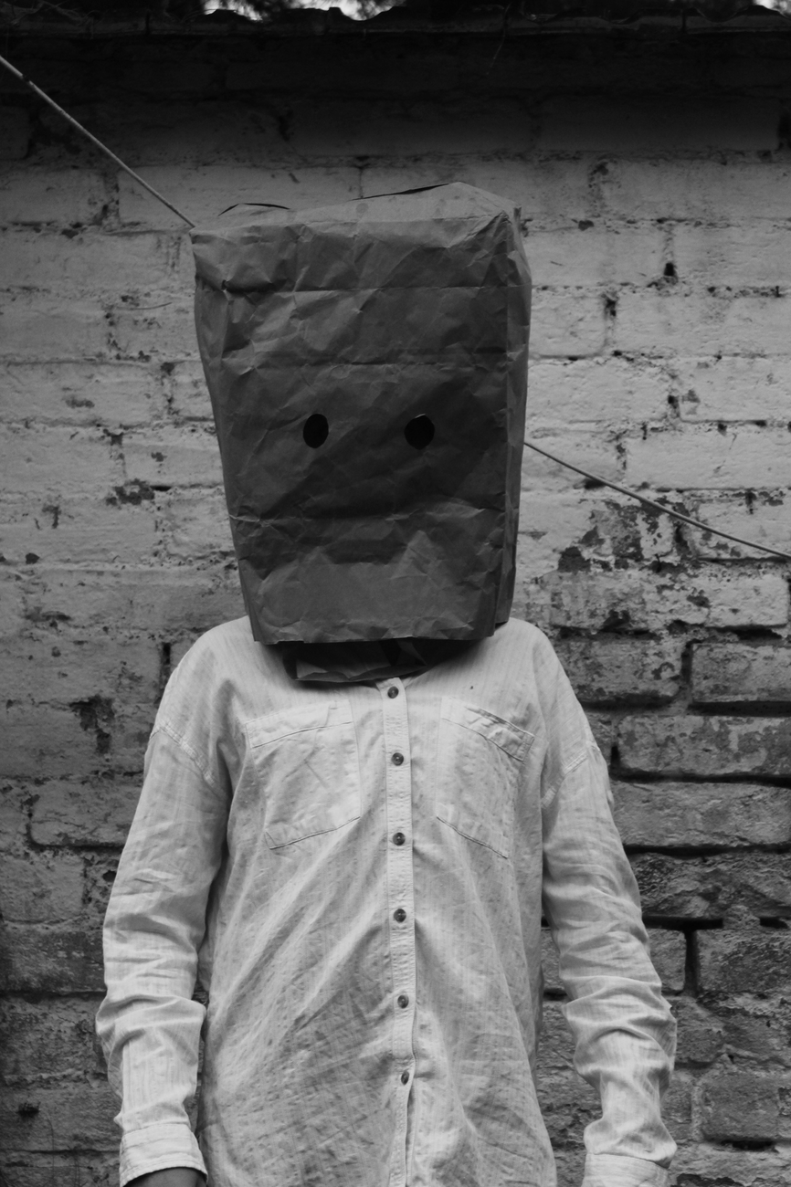 grayscale photo of man wearing a paper bag on his head